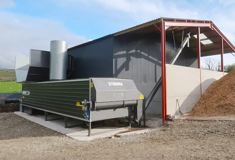 Image shows a barn structure with a biogas digestate dryer beside it that is used for digestate drying for animal bedding